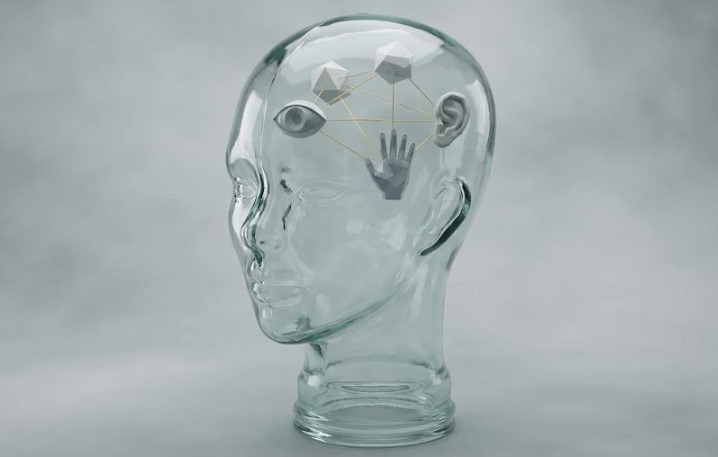 A translucent glass mannequin head rendered in watercolor. Inside the head float symbolic geometric icons of the senses: an eye, a hand, and an ear, all connected by thin golden threads that map the structure of perception.